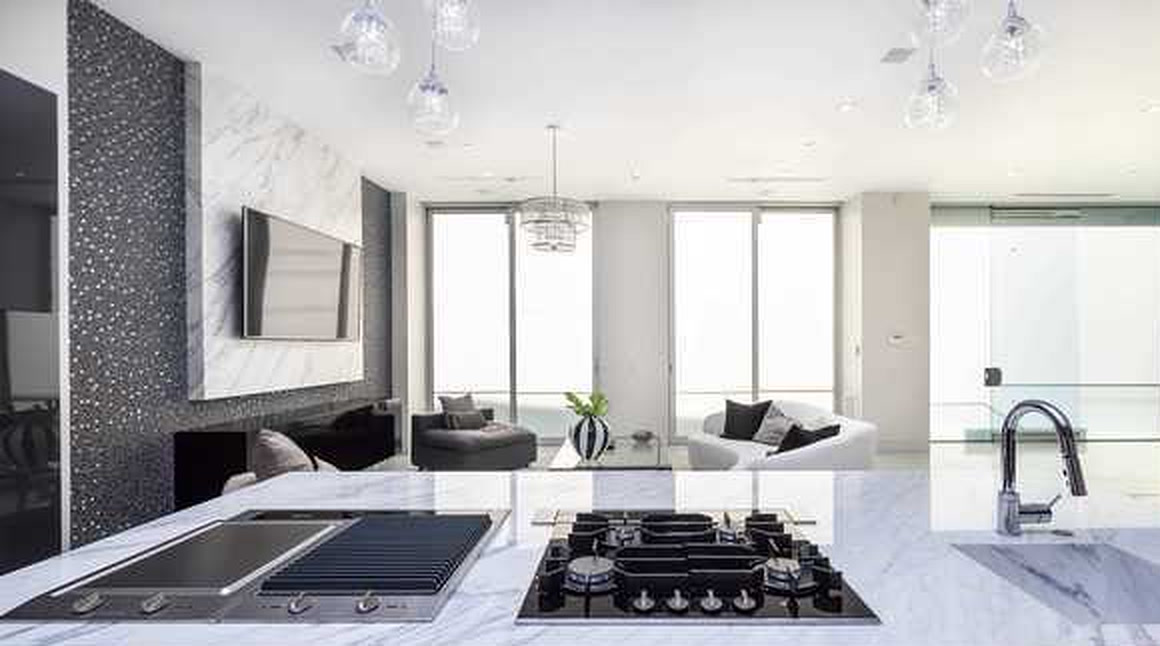 Bel Air living area with marble fireplace wall, island cooktop and terrace glazing
