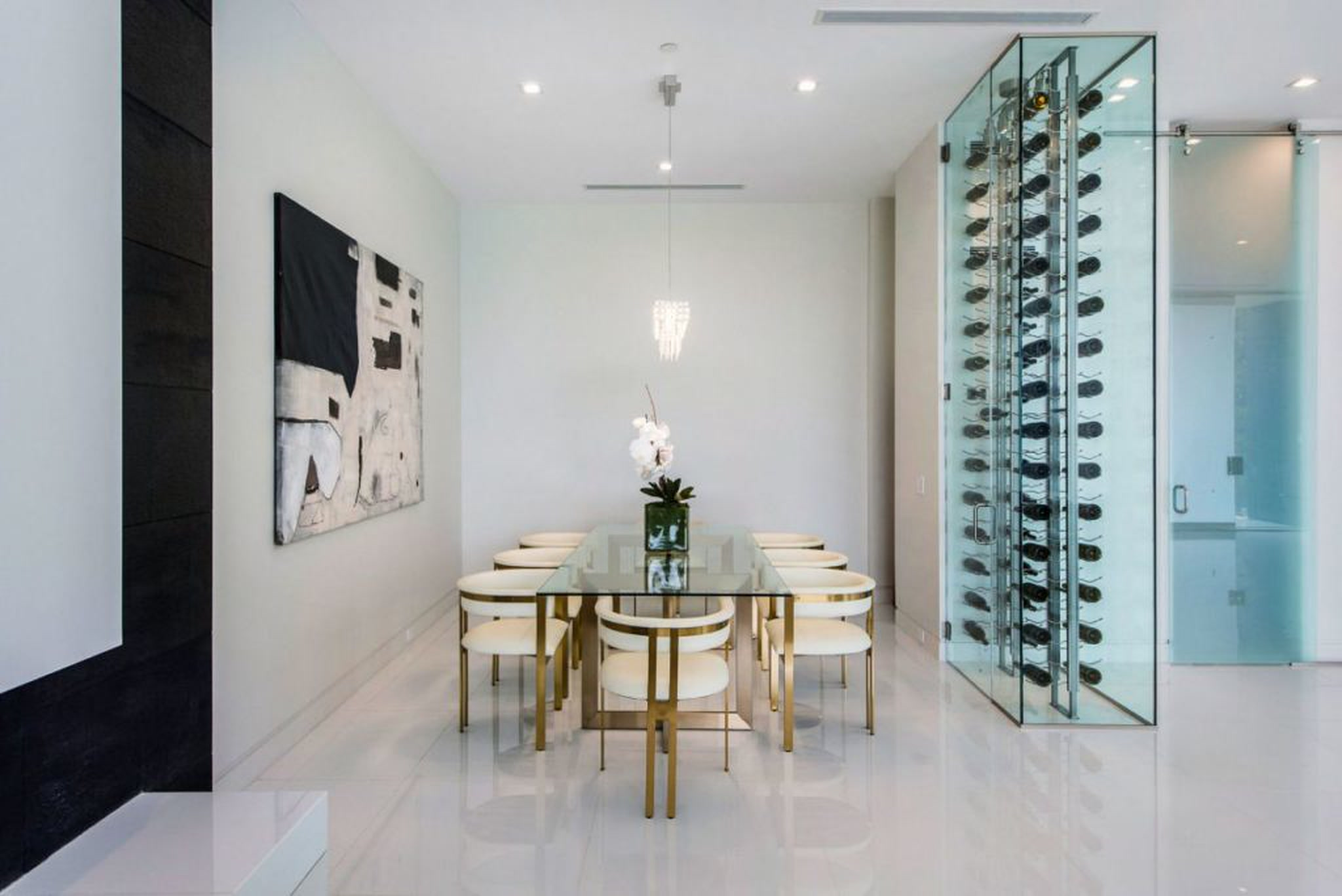 Bel Air dining room with glass table, brass seating and glazed wine display