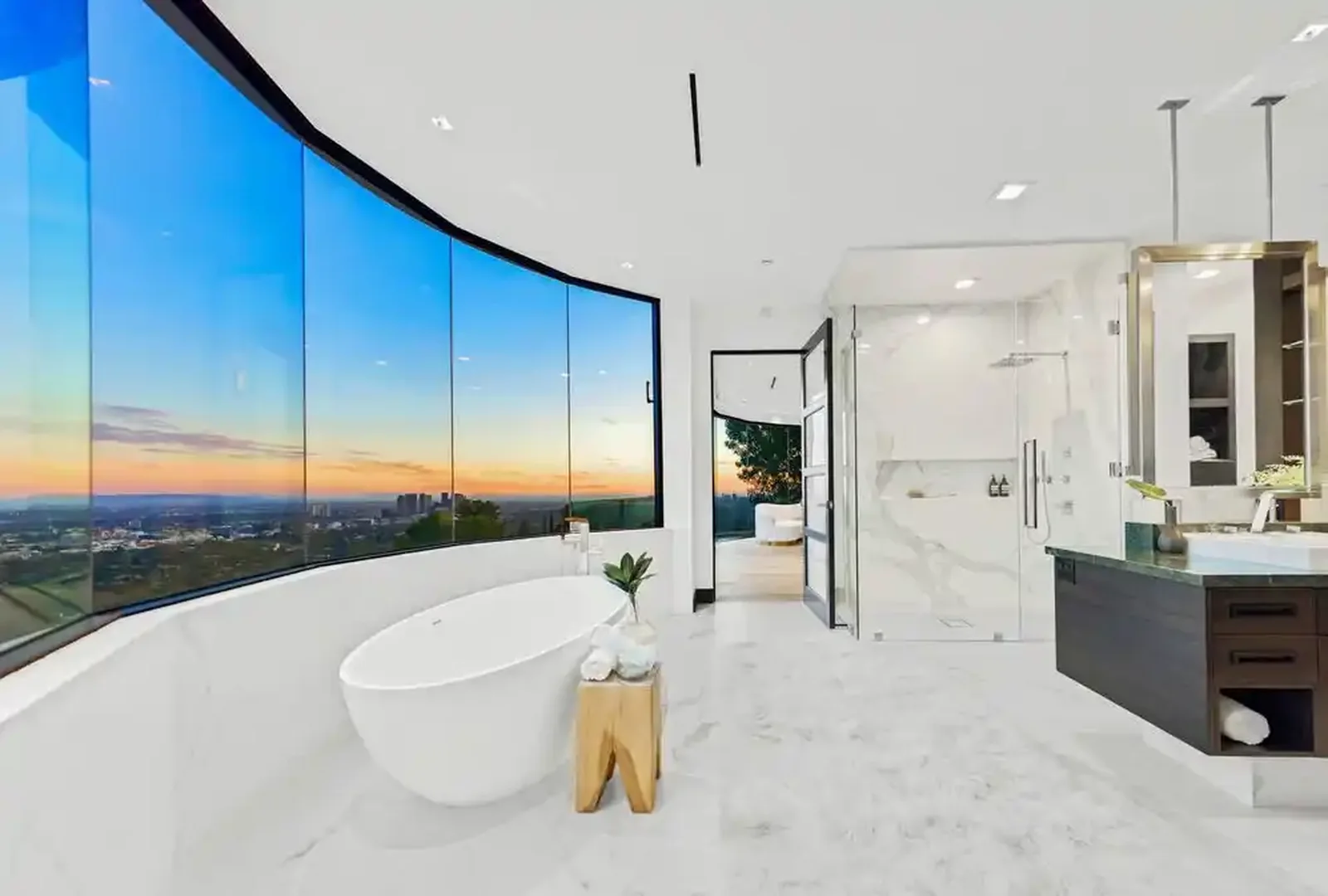 Primary bathroom with freestanding tub and curved city-view glazing