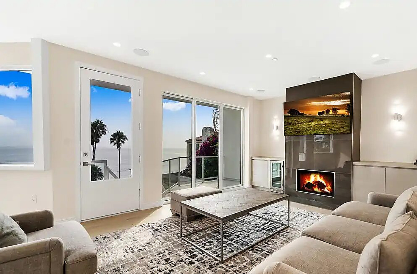 Living room with fireplace and full-height glass to a coastal view