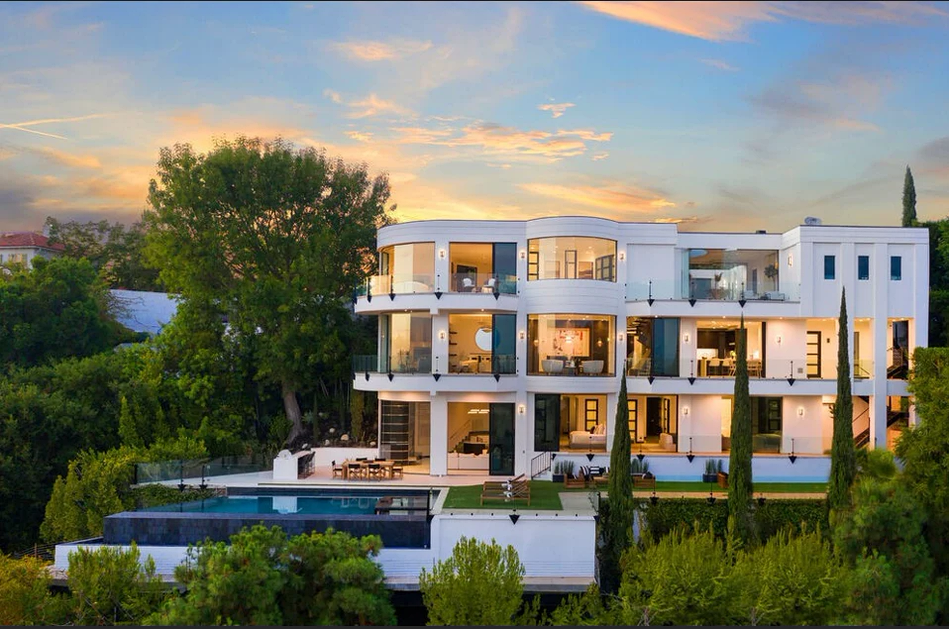 Malibu residence exterior at sunset with terraced living levels, pool deck and mature landscape